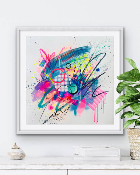A large white framed dynamic abstract artwork by Kate Elkington featuring bold splashes of neon pink, jade green, yellow, orange, and blue, combined with graphic circle shapes, stripes, black accents and white grid patterns. Expressive brush strokes, crayon scribbles and paint drips add movement and energy, creating a vibrant and playful composition that radiates joy and positivity.