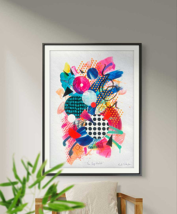 A black framed, large A1 sized, colourful abstract fine art print by Kate Elkington filled with vibrant hues of neon pink, blue, orange, and yellow. The composition features layered circular shapes, bold polka dots, and geometric patterns such as triangles and grids. Energetic brushstrokes and splashes of paint create a lively, dynamic effect, while contrasting tones of black and white add balance. The piece exudes a playful and uplifting vibe.