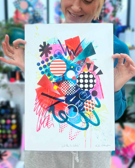 The artist Kate Elkington holding an A3 sized, vibrant, colourful abstract artwork featuring bold, graphic shapes, dynamic brushstrokes, and playful patterns. The composition includes splashes of neon pink, orange, and blue, layered with geometric elements such as dots, grids, and curved black lines, radiating energy and movement.
