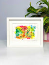 A white framed A5 sized vibrant abstract giclée art print by Kate Elkington, featuring a playful mix of shapes and colours. Bright yellows, oranges, blues, greens and hot pinks are blended with soft washes of watercolour, overlaid with whimsical patterns like dots, stars, and swirls. Free-flowing lines and dynamic brushstrokes create a sense of movement, while geometric elements such as squares and circles add structure. The overall composition is lighthearted and uplifting, exuding creativity and joy.