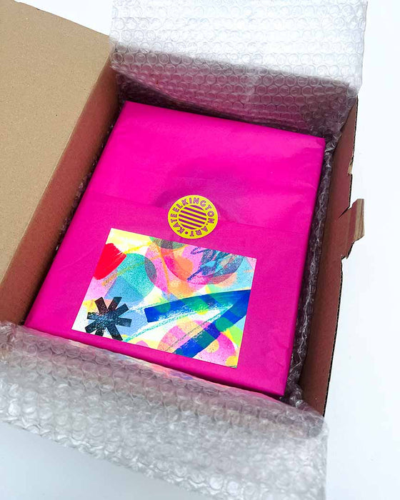 Beautiful packaging of a small framed artwork by Kate Elkington. The framed artwork is wrapped in hot pink acid free tissue paper, secured with a yellow and pink logo sticker, protected with bubble wrap and placed into a perfectly sized cardboard box. A small, colourful, postcard sized original mixed media artwork is included as a thank you.