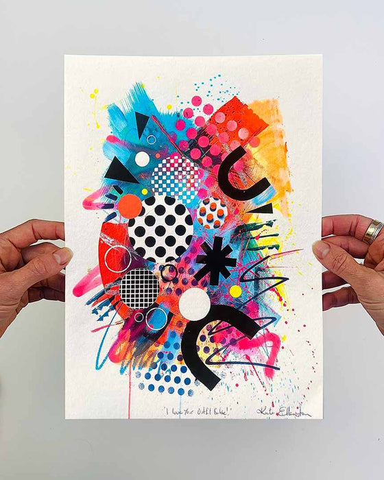 The artist Kate Elkington's hands holding a vibrant, colourful abstract artwork, featuring bold, graphic shapes, dynamic brushstrokes, and playful patterns. The composition includes splashes of neon pink, orange, bright red, and blue, layered with geometric elements such as dots, grids, and curved black lines, radiating energy and movement.