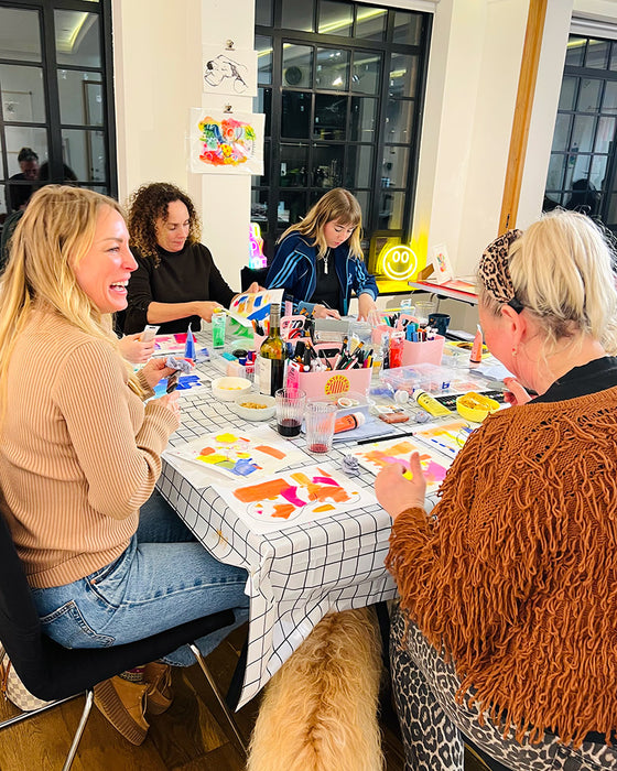 Group of people sitting around a table with colourful art supplies, engaged in a creative activity at the Happy DoodlesCreative Social Club with Kate Elkington