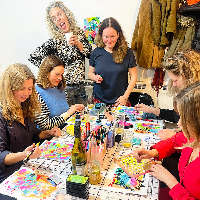 Group of people engaged in a craft activity at a table with art supplies.